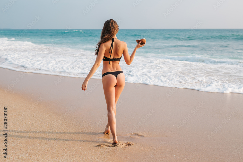 Mockingbird helgen skrig Backside view of tanned girl with sexy ass in black bikini walking on  beach, holding coconut. Young woman traveler with perfect body on vacation.  Concept swimwear Stock Photo | Adobe Stock