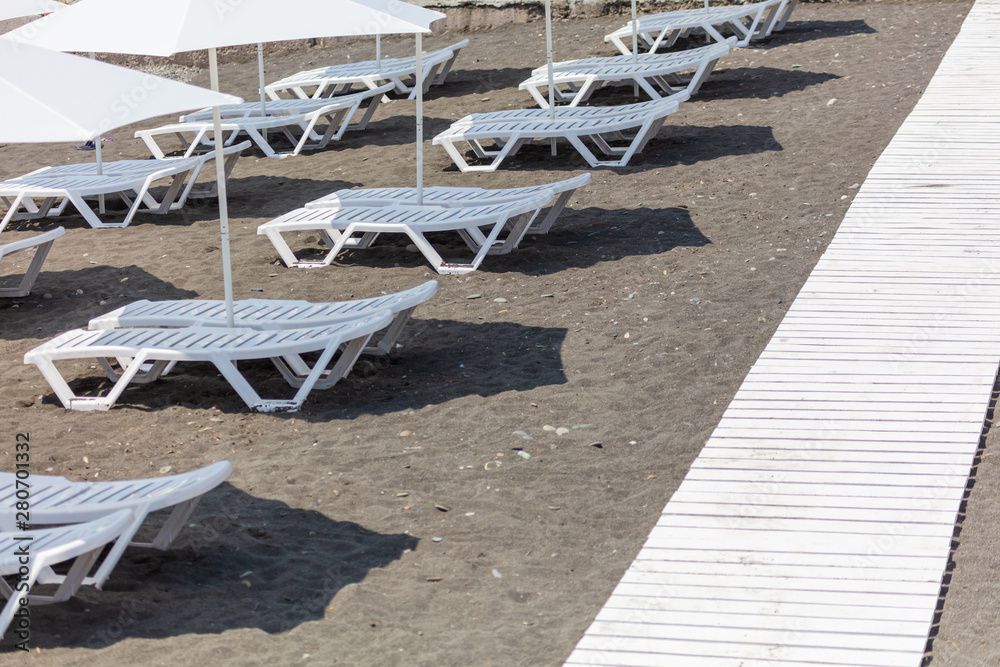 Sun beds with umbrellas on a pebble beach Sun beds with umbrellas on a pebble beach