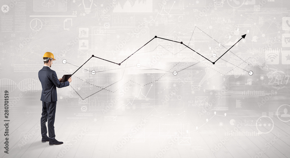 Engineer with construction helmet holding a plan and standing with graphs, charts and reports on the background Engineer with construction helmet holding a plan and standing with graphs, charts and reports on the background