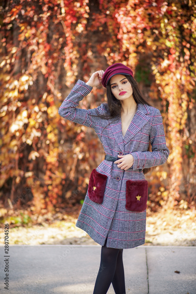 Young beautiful girl wearing winter coat and cap in autumn leaves background. Young beautiful girl wearing winter coat and cap in autumn leaves background.