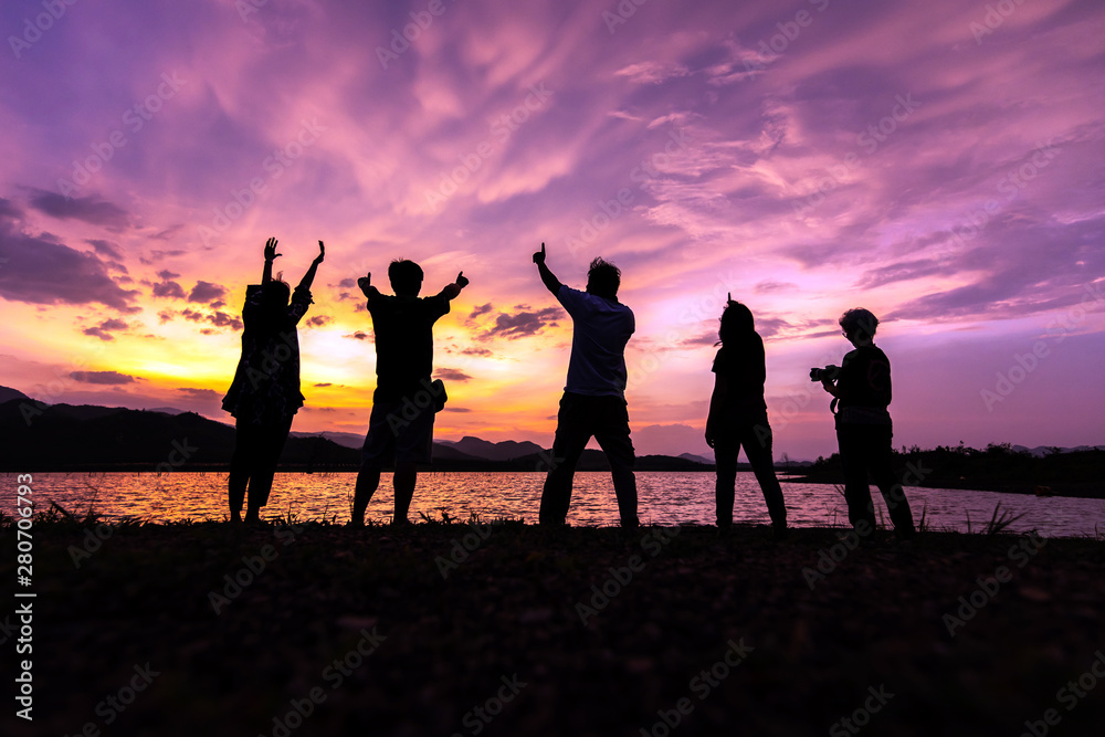 Silhouette of friends enjoy while dramatic sunset sky with beautiful clouds. Traveling and vacation concept.