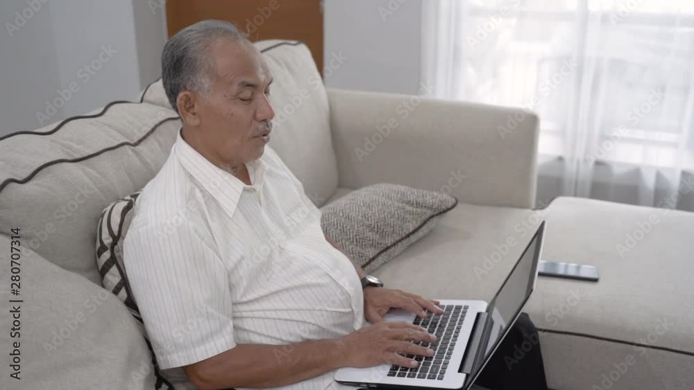 busy senior asian man working from home. old man using laptop at livingroom busy senior asian man working from home. old man using laptop at livingroom