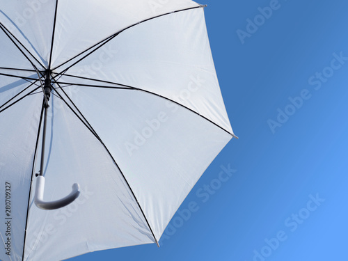 Open white umbrella against a blue sky. Weather forecast.