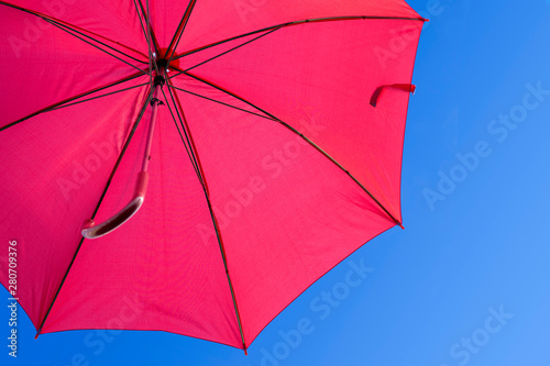 Open red umbrella against a blue sky. Weather forecast.