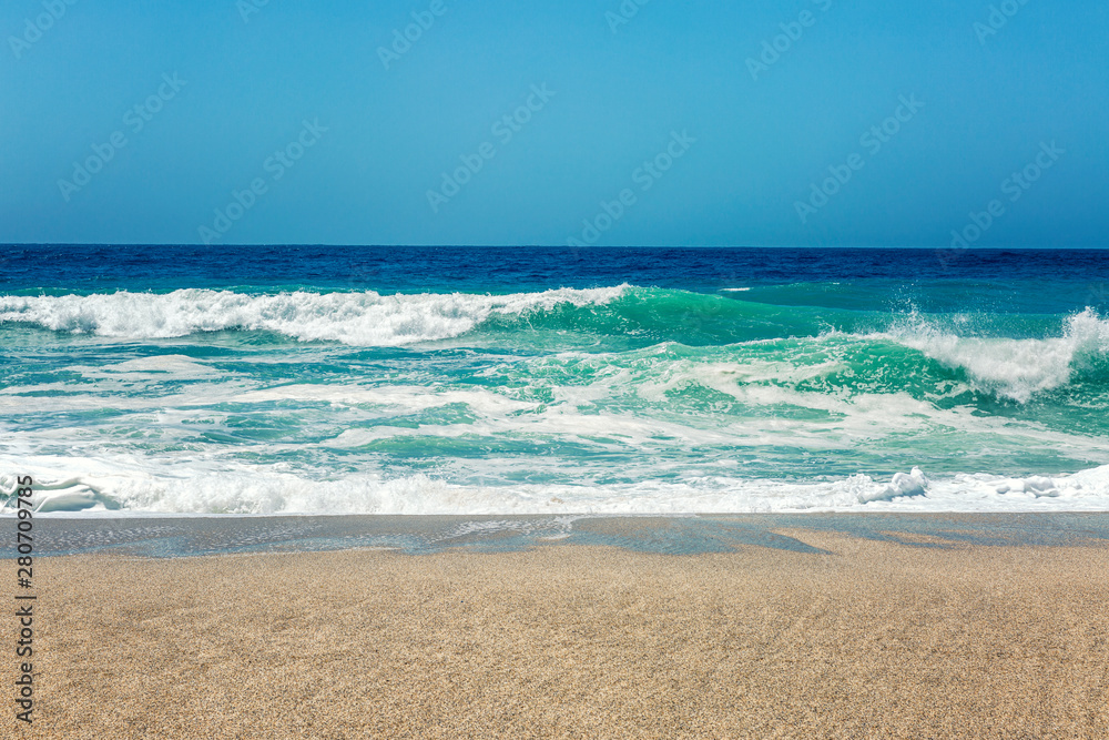 Sandy coast of the turquoise sea. Surging waves, sunny windy day. Space for text. Sandy coast of the turquoise sea. Surging waves, sunny windy day. Space for text.