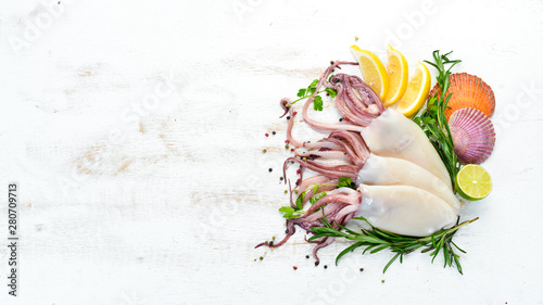 Raw fresh squid with spices. Seafood on a white wooden background. Top view. Free copy space.