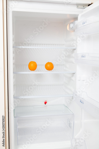 Two oranges lie on empty shelf of  refrigerator