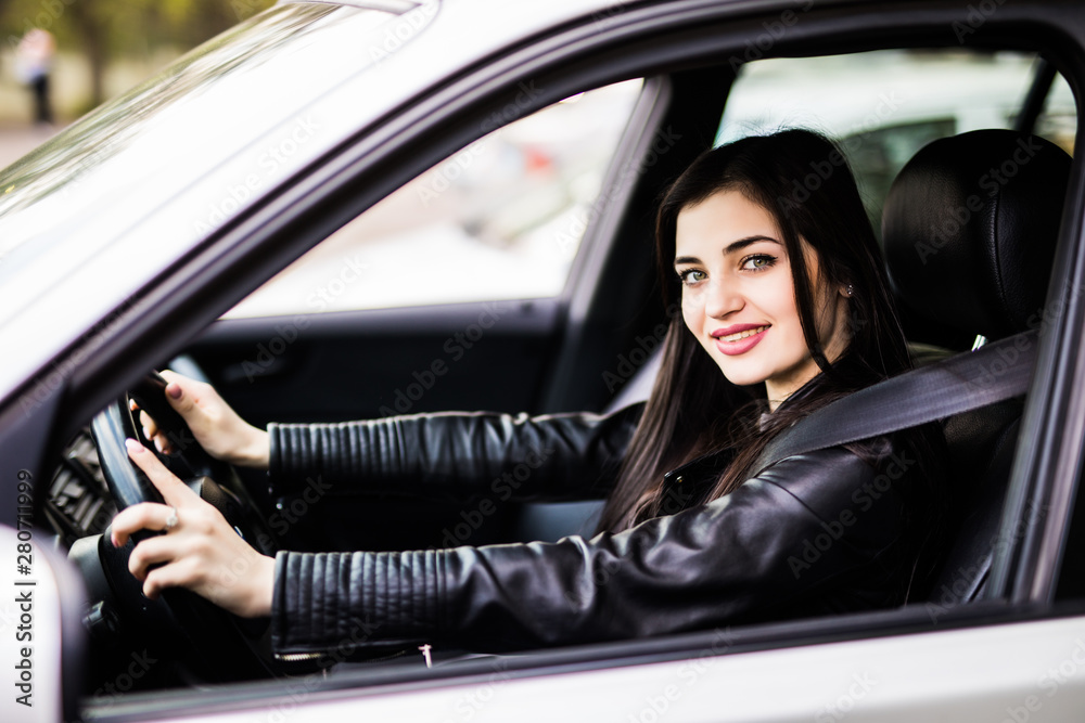 Beautiful young happy smiling woman driving her new car