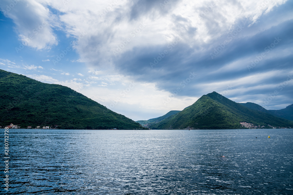 Montenegro, Green forest covered mountains forming giant fjord of kotor bay, seen from perast old town coast with beautiful sky