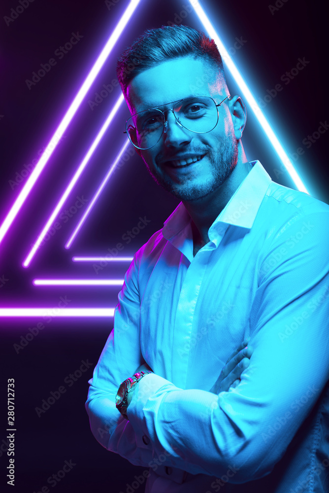 Young handsome model posing in a studio in a trendy neon light. Fashionable man in a stylish suit. Vibrant color. Bright colorful light effects. Disco style. Overlay. Gel filter. Supersaturated Young handsome model posing in a studio in a trendy neon light. Fashionable man in a stylish suit. Vibrant color. Bright colorful light effects. Disco style. Overlay. Gel filter. Supersaturated
