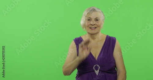 An elderly woman waving to camera and smiles. Old grandmother. Chroma key