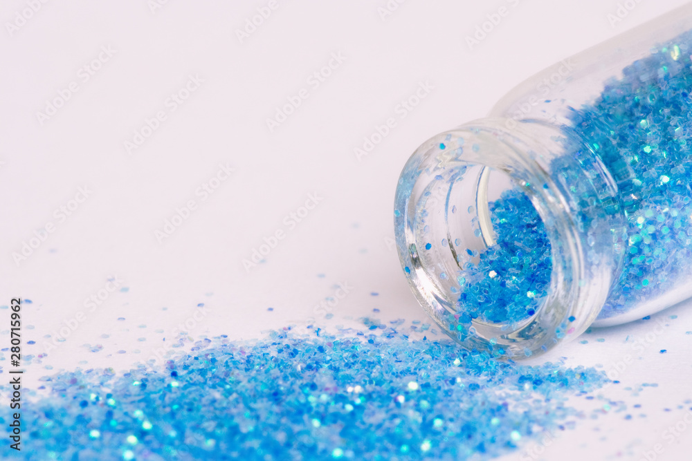 Purpurina brillante azul celeste derramada de un tarro sobre fondo blanco. Purpurina brillante azul celeste derramada de un tarro sobre fondo blanco.