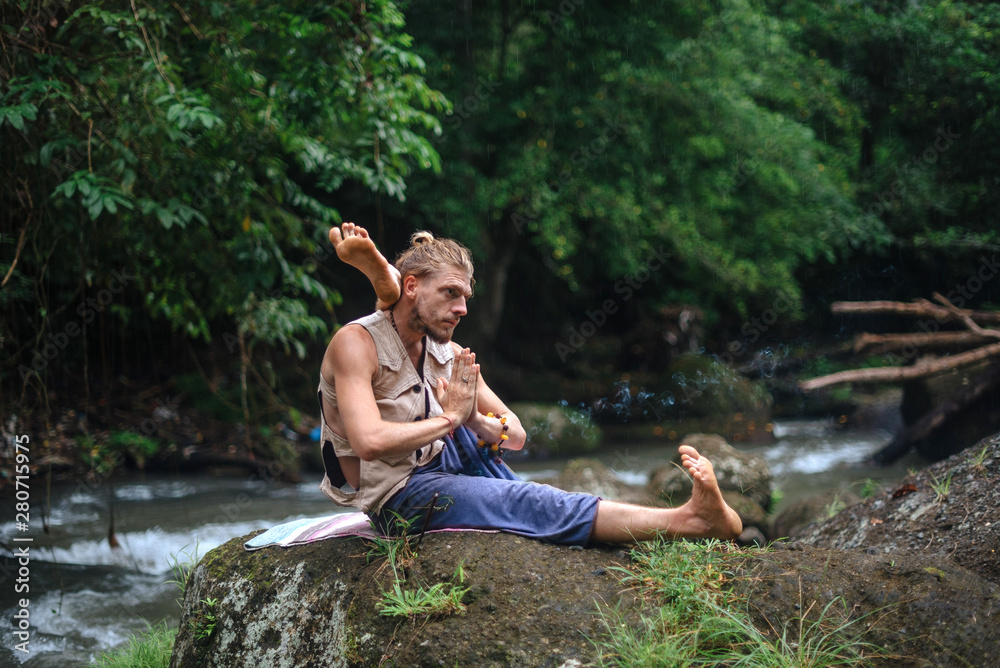 Yoga practice and meditation in nature. Man practicing near river Yoga practice and meditation in nature. Man practicing near river