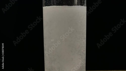 Glass of water with aspirin white tab. Sparkling Bubbles in glass of water.  Effervescent tablet falls on a bottom of a glass