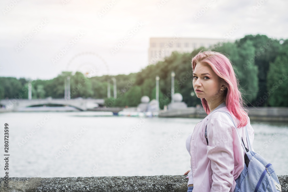 young woman holding backpack while standing against city river young woman holding backpack while standing against city river
