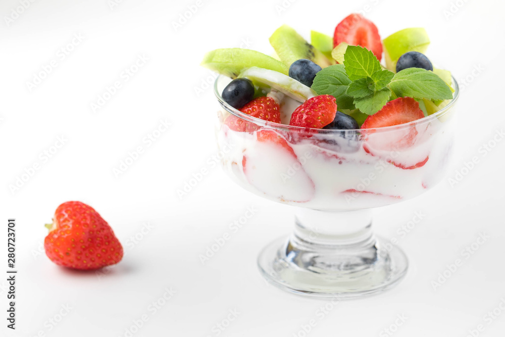 Bowl of homemade granola with yogurt and fresh berries: strawberry, kiwi and blueberry on white background from side view Bowl of homemade granola with yogurt and fresh berries: strawberry, kiwi and blueberry on white background from side view