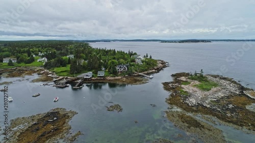 Great Aerial Zoom in of Beautiful oceanfront house on small harbor in Southport Maine.  Amazing cottage with pine forest and beach, Island with northern landscape in United State of America. photo
