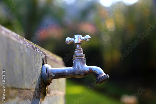 A faucet closed on a stone wall. Dark background.