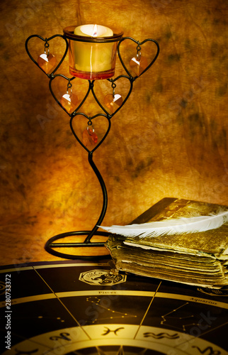 Fotografie old book with feather and candle and horoscope like esoteric fortune teller conc