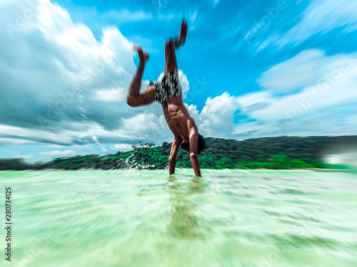 Young man doing acrobatics in the water in tropical location