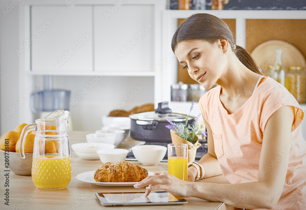 Smiling pretty woman looking at mobile phone and holding glass