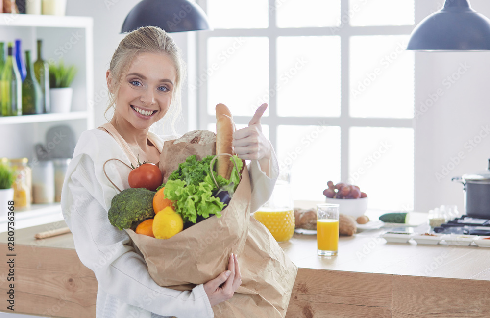 Young woman holding grocery shopping bag with vegetables Standi Young woman holding grocery shopping bag with vegetables Standi