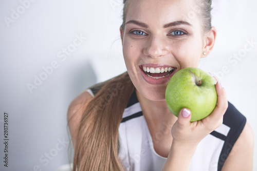 Young beautiful smiling girl with a green apple in hands