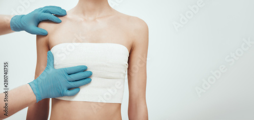 Increase your breast size. Cropped photo of woman waiting for plastic surgery while surgeons in blue medical gloves measuring her breast