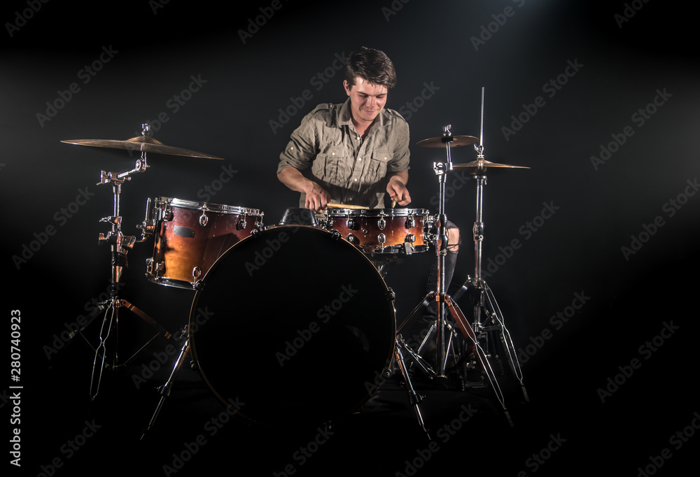 Fototapeta premium Professional drummer playing on drum set on stage on the black background