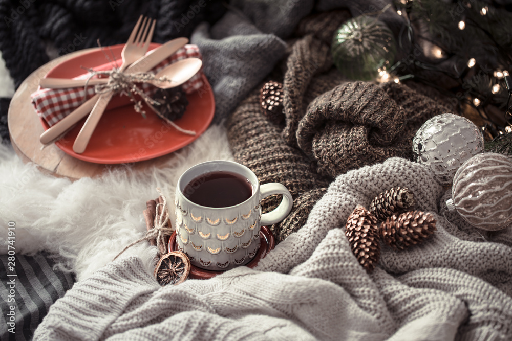 Cozy Christmas morning with cup of tea in bed. Still life scene with sweaters. Steaming cup of hot coffee, tea. Christmas concept.