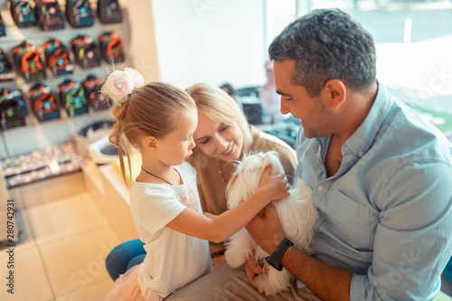 Daughter coming to pet shop with parents and holding dog
