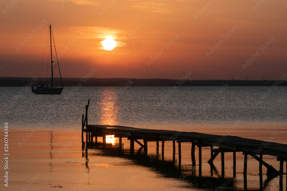 romantic seascape with wooden jetty and sail boat