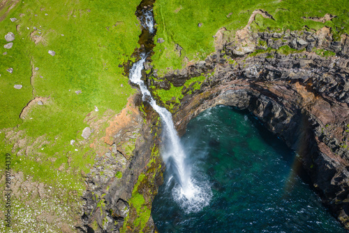 Aerial view of Mulafossur waterfall in Gasadalur village in Faroe Islands, North Atlantic Ocean. Photo made by drone from above. Nordic Natural Landscape. © Curioso.Photography