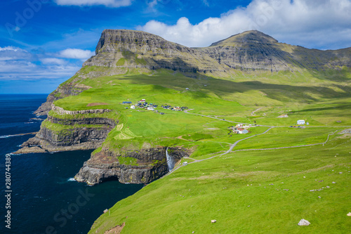 Aerial view of Mulafossur waterfall in Gasadalur village in Faroe Islands, North Atlantic Ocean. Photo made by drone from above. Nordic Natural Landscape.