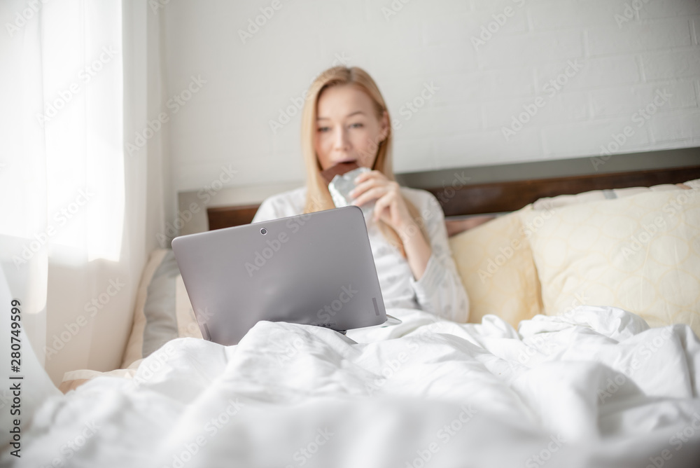 Work from home concept . Blonde Giirl typing and using laptop eating chocolate. Hygge Horizontal copyspace Work from home concept . Blonde Giirl typing and using laptop eating chocolate. Hygge Horizontal copyspace