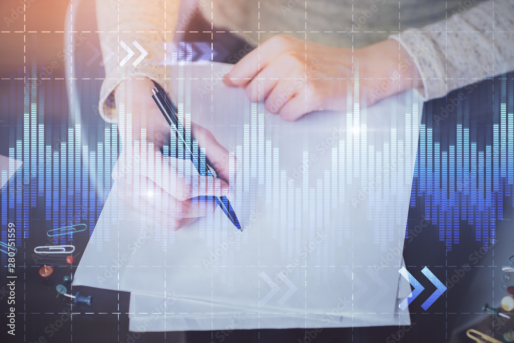 Hand taking notes in notepad. Forex chart holograms in front. Concept of research. Multi exposure Hand taking notes in notepad. Forex chart holograms in front. Concept of research. Multi exposure