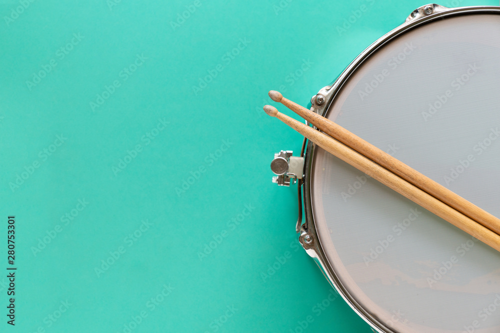 Drum and drum stick on green table background, top view, music concept - obrazy, fototapety, plakaty 