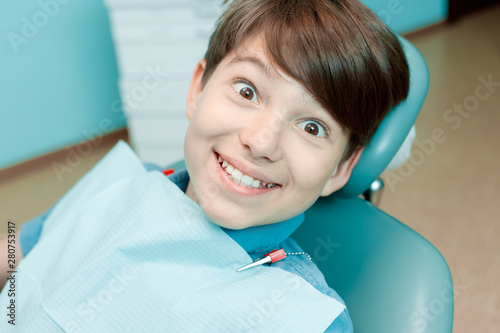 Little boy in dental chair. Smiling and satisfied patient at dentist's office after treatment. Healthy teeth, dental care concept.