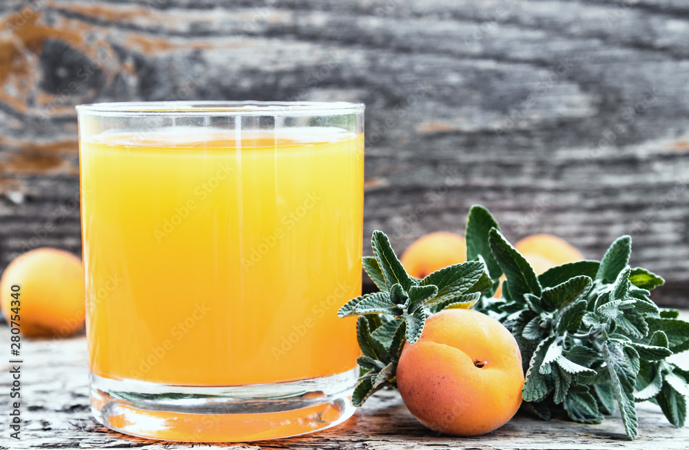 Fresh apricot juice with apricots and twigs of green mint on the background of old boards. Fresh apricot juice with apricots and twigs of green mint on the background of old boards.