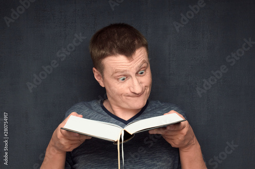 Принти на полотні Portrait of funny and perplexed man reading big book