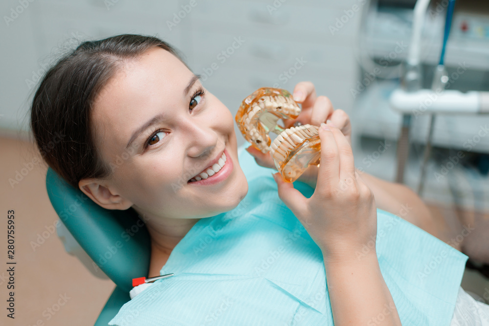Beautiful young woman in dental chair. Smiling and satisfied patient at dentist's office after treatment. Healthy teeth, dental care concept. Beautiful young woman in dental chair. Smiling and satisfied patient at dentist's office after treatment. Healthy teeth, dental care concept.