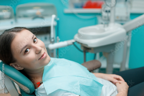 Patient in dental chair. Beautiful young woman having dental treatment at dentist's office. Healthy teeth, dental care concept.