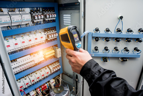 Technician use infrared thermal imaging camera to check temperature at fuse-box