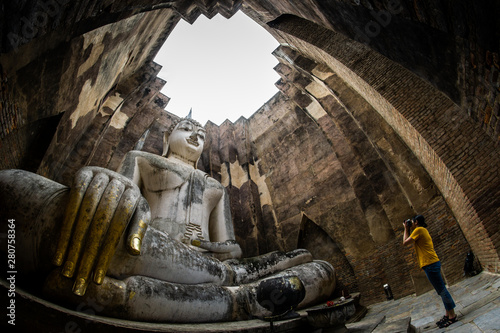 Photos female traveler photographing temples at Sukothai historical park, Unesco world heritage, Thailand, the body to head part of the big buddha image at Wat Sri Chum in Sukhothai