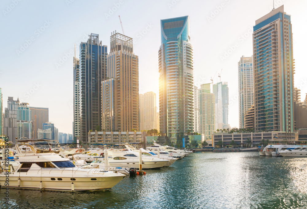 Naklejka premium Dubai, UAE United Arabs Emirates. Dubai marina skyscrapers and yachts at sunset. Apartments, hotels and office buildings, modern residential development of UAE