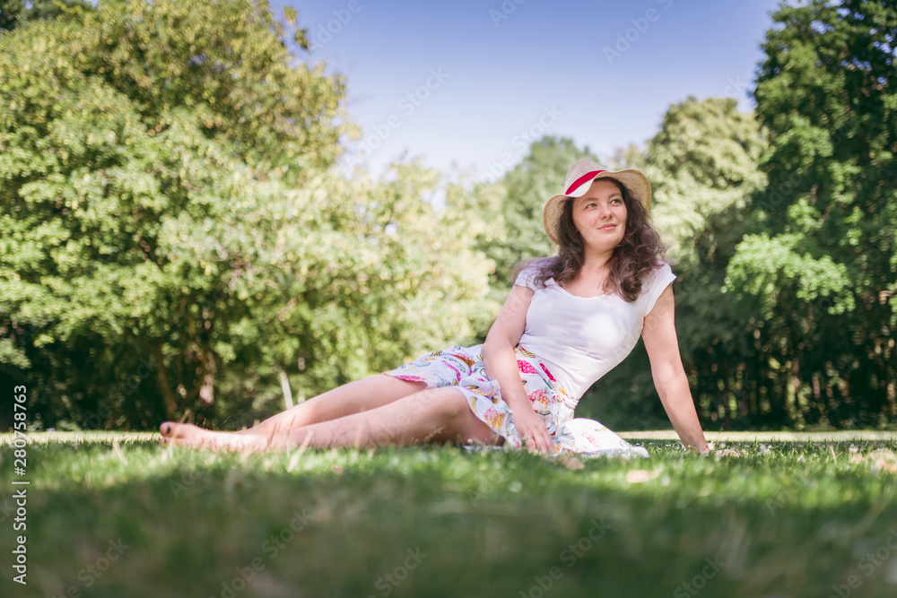 Summer portrait of young  woman sitting on the grass, in sunny day. Beautiful, romantic woman.