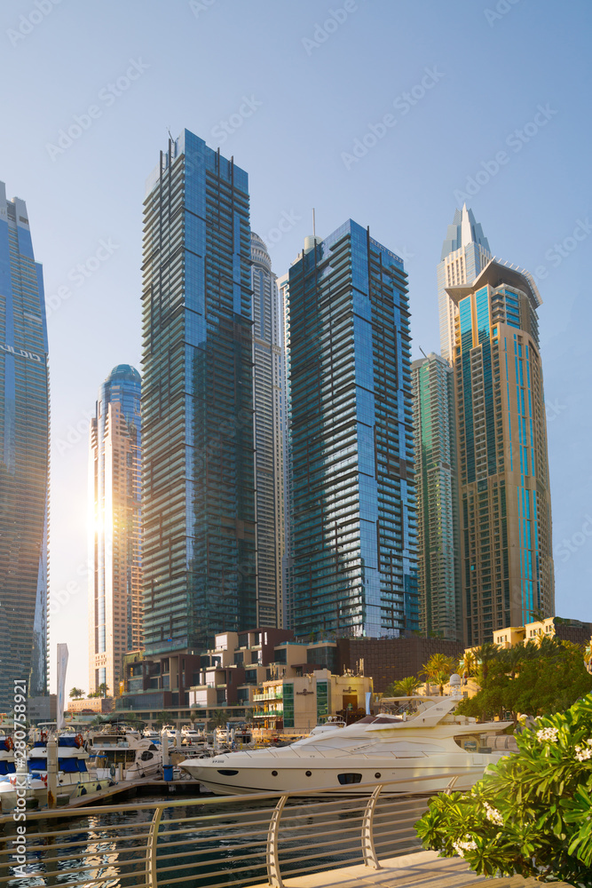 Obraz premium Dubai, UAE United Arabs Emirates. Dubai marina skyscrapers and yachts at sunset. Apartments, hotels and office buildings, modern residential development of UAE