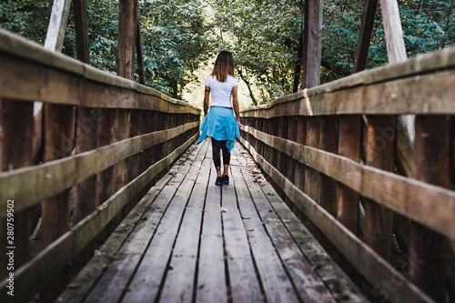 A girl walking on a wooden pier in the middle of nature