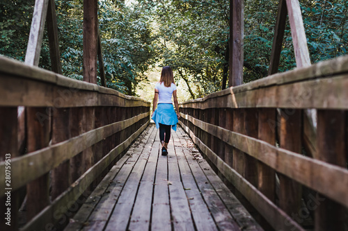 A girl walking on a wooden pier in the middle of nature