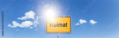 Straßenschild „Heimat“ vor Himmel mit Weissen Wolken